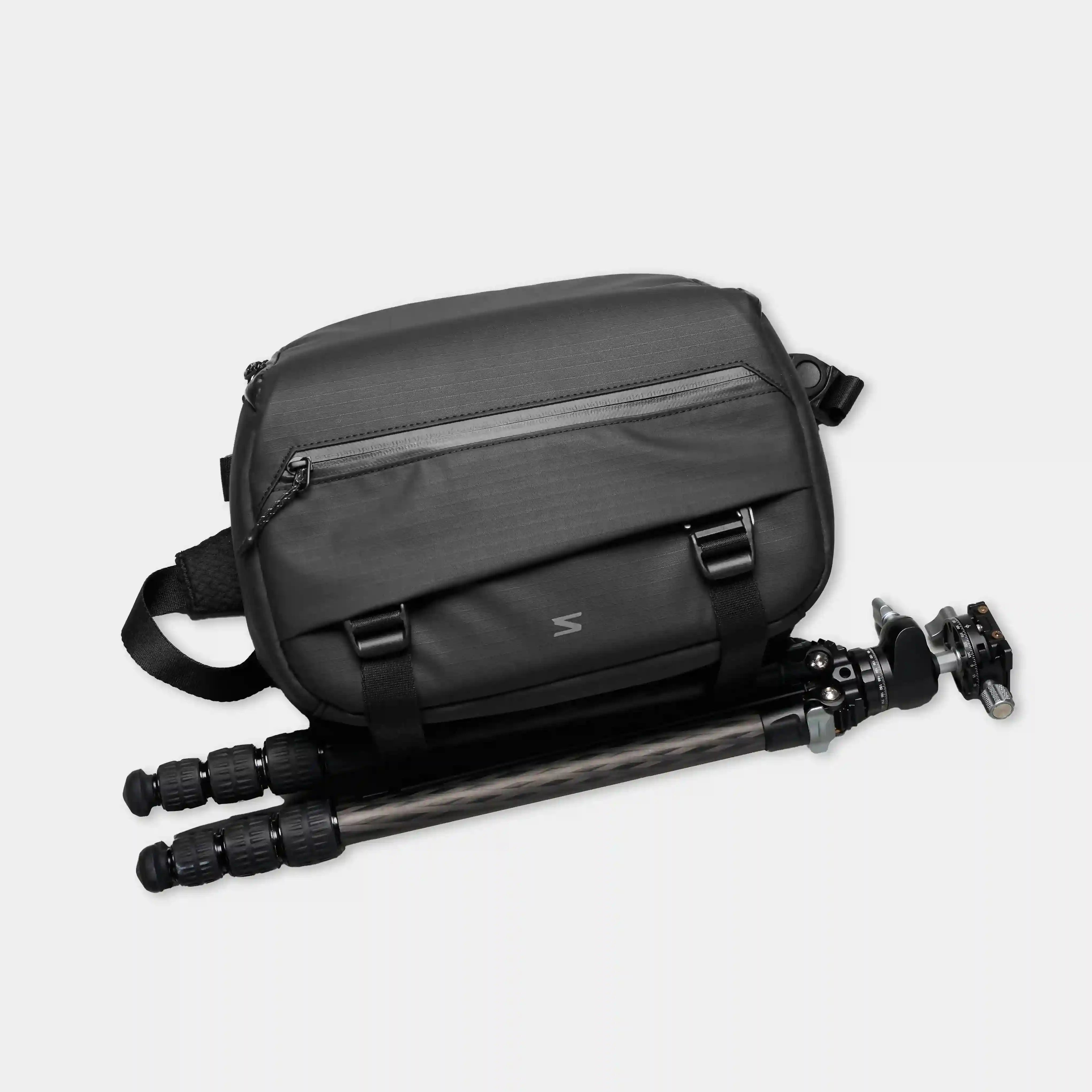 Black camera bag with a tripod on a light gray background