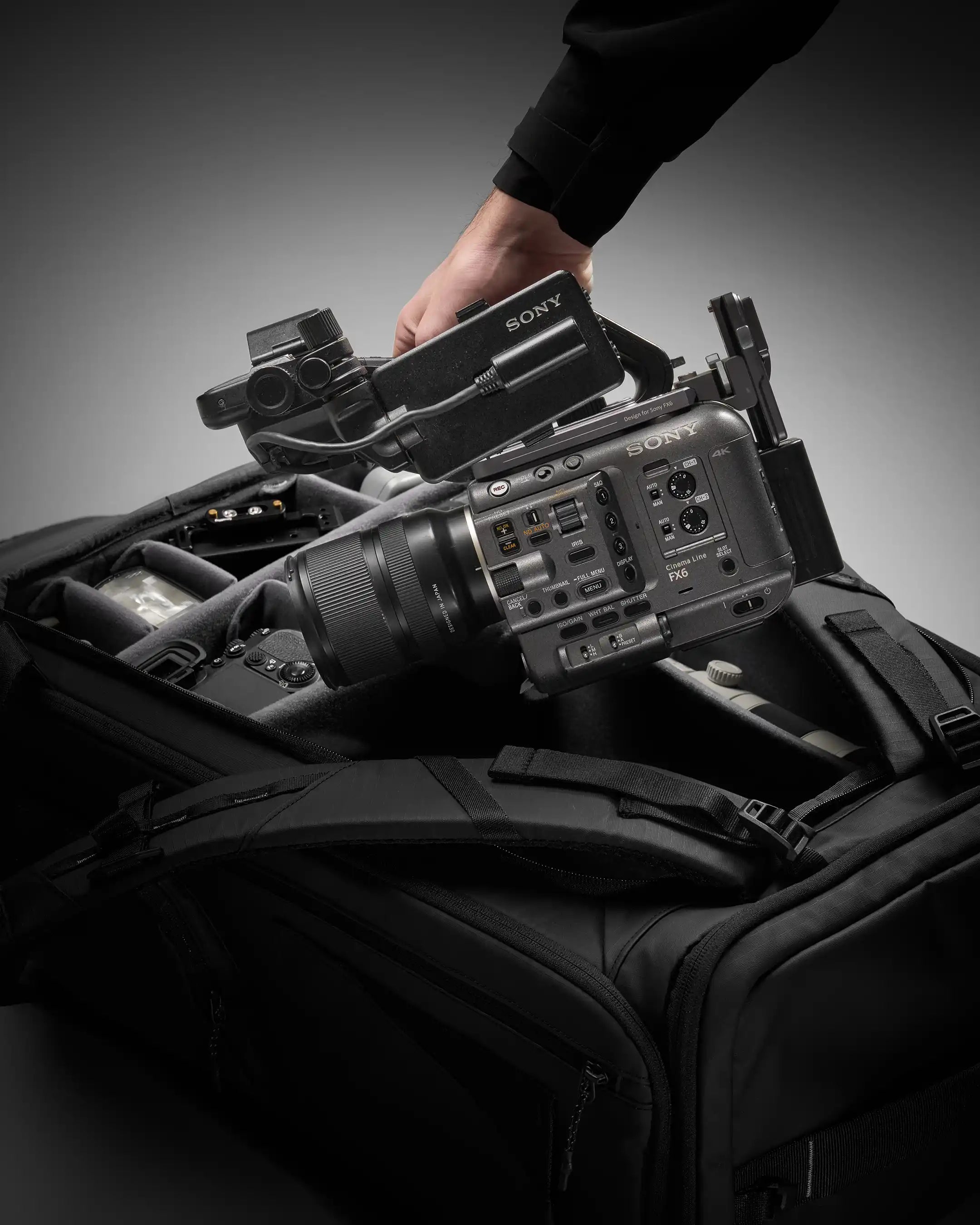 Sony camera on a shoulder bag with a hand adjusting the camera