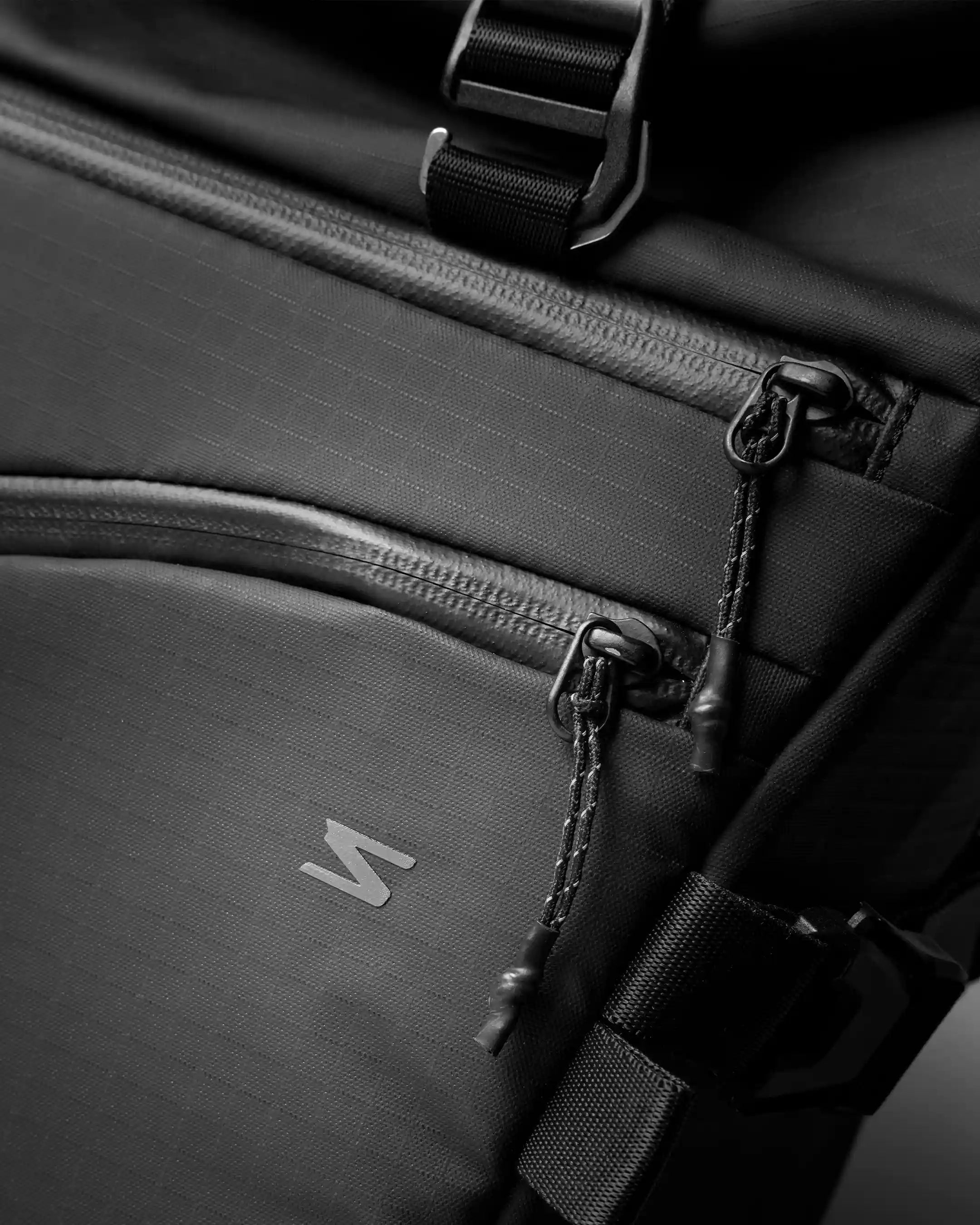 Close-up of a black backpack with a brand logo on a dark background