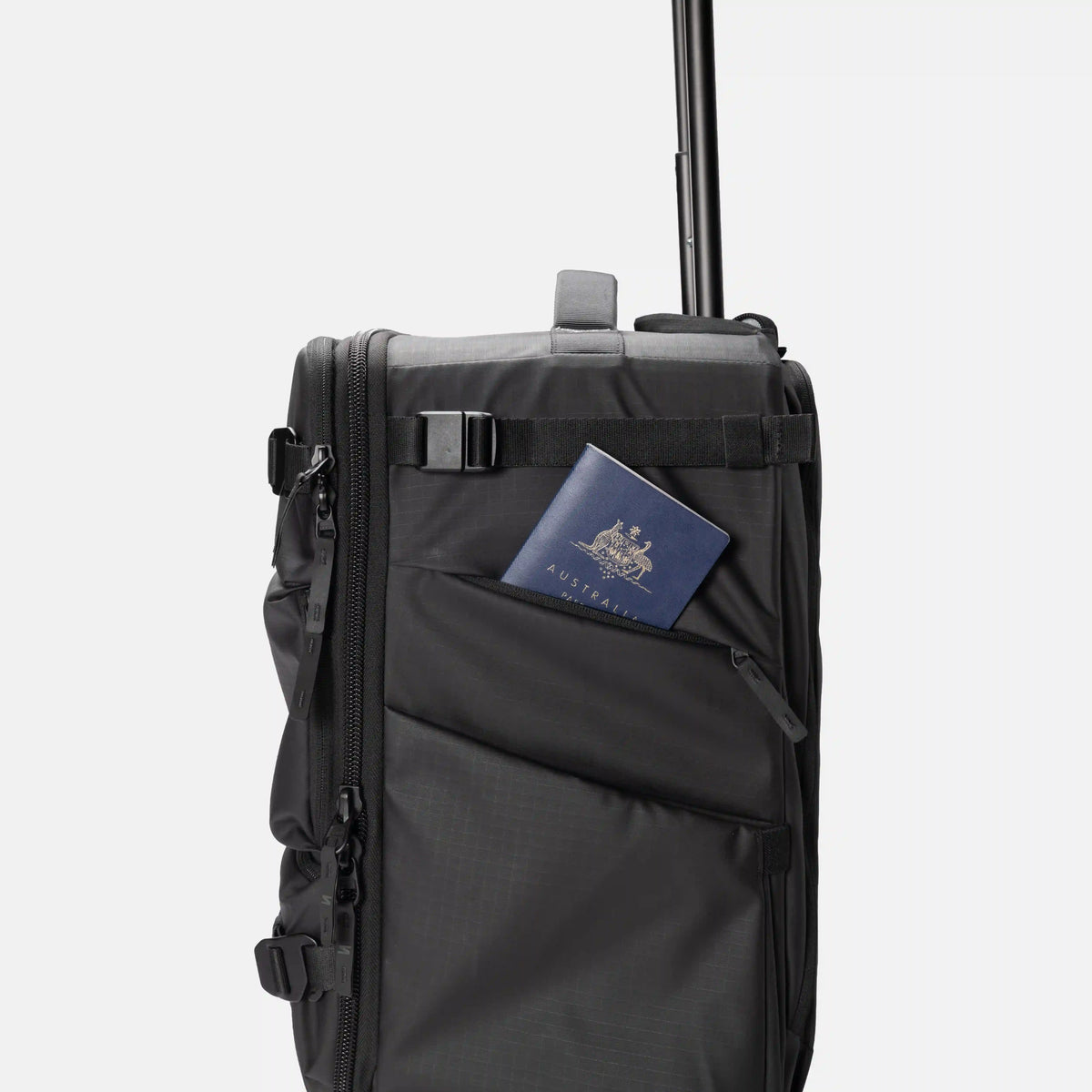 A black rolling suitcase with an extended telescoping handle, featuring a side utility pocket holding a passport.