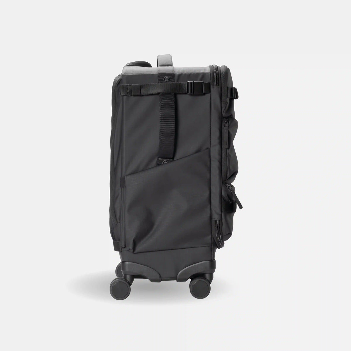 A dark gray rolling suitcase shown from the back, featuring a telescoping handle, four spinner wheels, a main zippered compartment, and a vertical compression strap with a buckle, set against a light gray background.