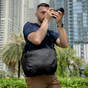 man with laptop and camera sling bag