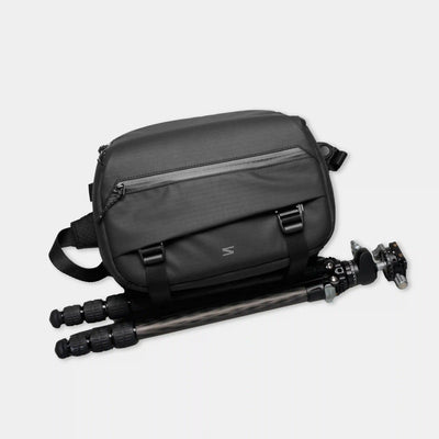 Black camera bag with a tripod on a light gray background