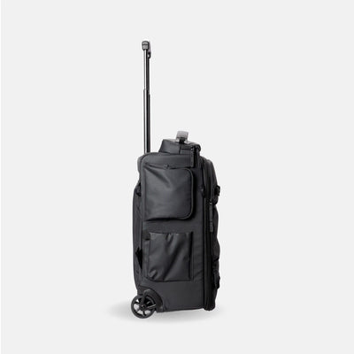 A black rolling duffel bag with an extended telescoping handle and two wheels, shown from a three-quarter side view against a light gray background.