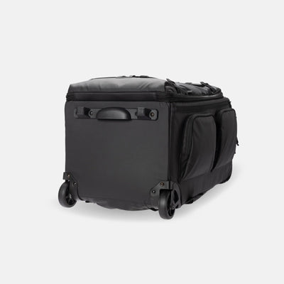 A black soft-sided rolling duffel bag with dual spinner wheels, a top zip closure, and side pockets, photographed on a clean light gray studio background.
