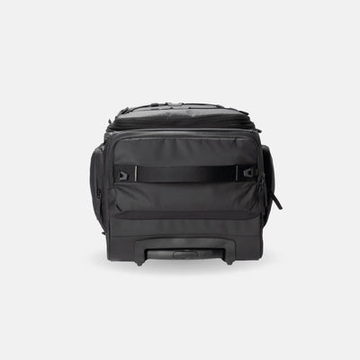 A black rolling duffel bag with a telescoping handle, side pockets, and a top zip closure, photographed against a light gray studio background.