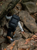 Person climbing rocky terrain wearing a black backpack