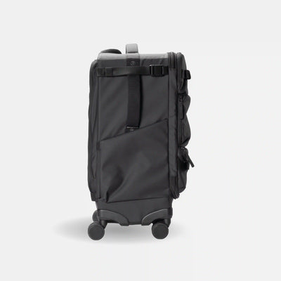 A dark gray rolling suitcase shown from the back, featuring a telescoping handle, four spinner wheels, a main zippered compartment, and a vertical compression strap with a buckle, set against a light gray background.