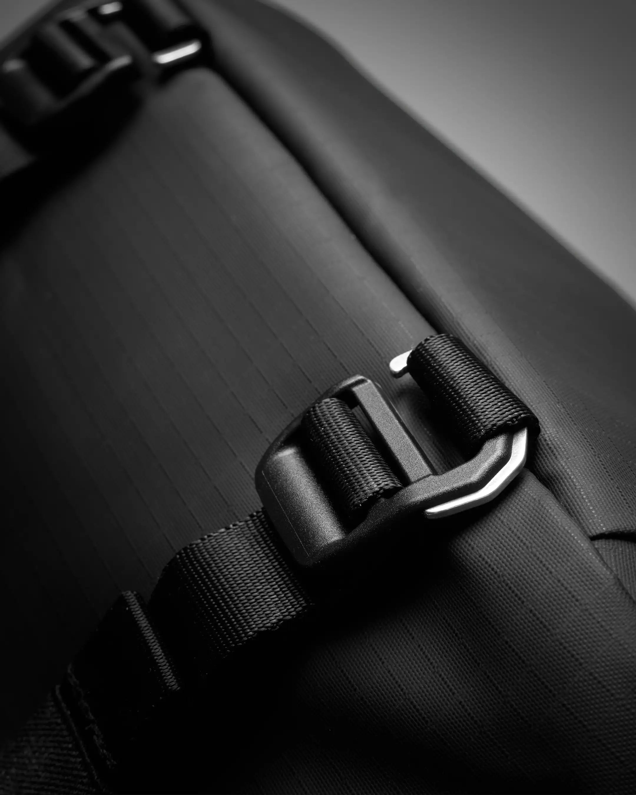 Close-up of a black suitcase with a strap and buckle on a dark background