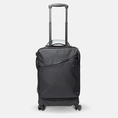 A black rolling suitcase with an extended telescoping handle, a front zippered pocket, and four spinner wheels, shown on a light gray background.