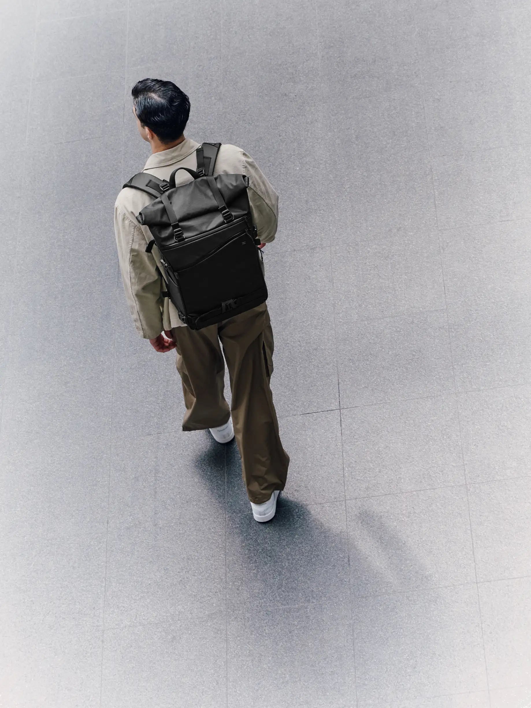 Person walking with a black backpack on a gray floor