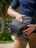Nomad camera and laptop sling bag worn by person on the go. Secure compartments for camera gear and tech essentials.